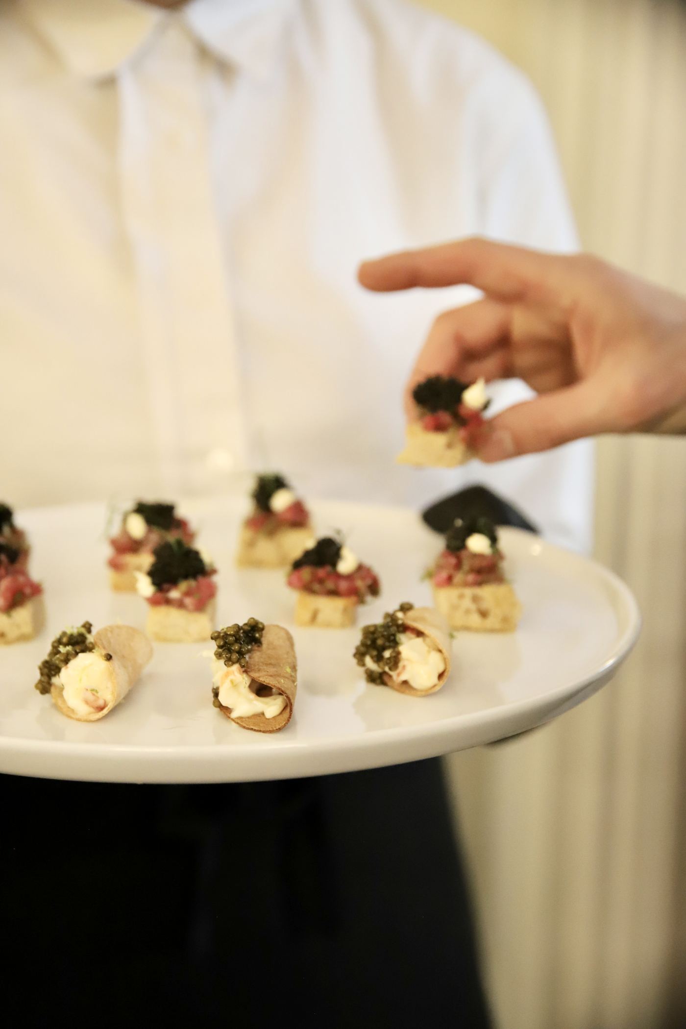 A tray of beef tartare canapés and caviar cannoli offered to guests.