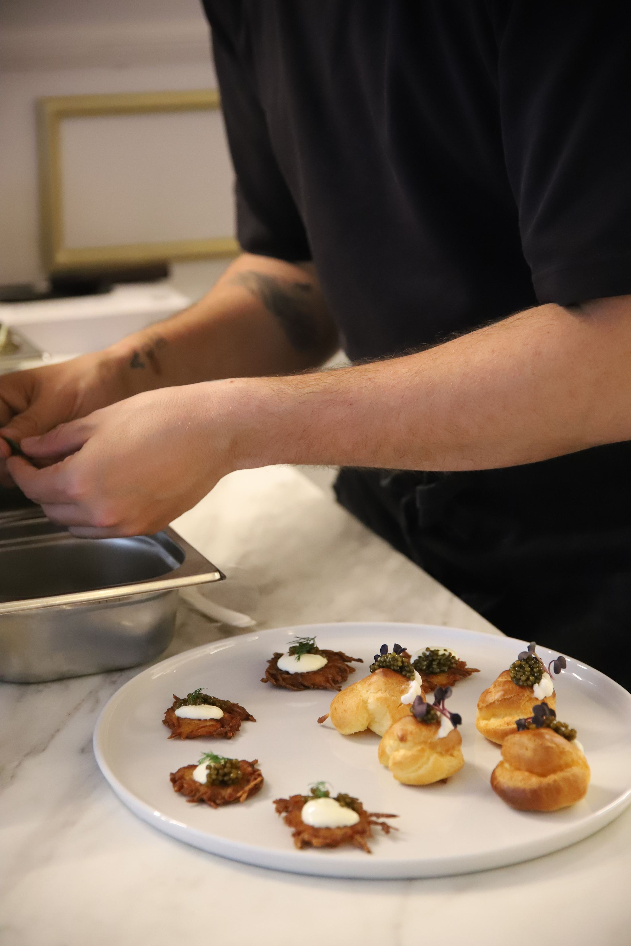 Plating in progress, caviar set onto canapés by hand.